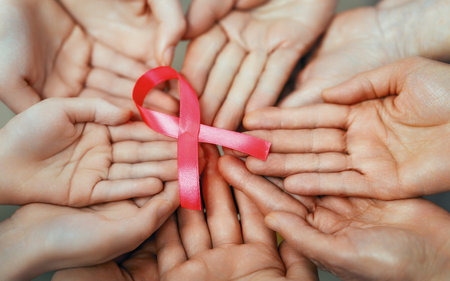 Hands of women with pink satin ribbon symbolizing concept of illness awareness, expressing solidarity and support for cancer patients and survivors. Different generations of peopleの写真素材
