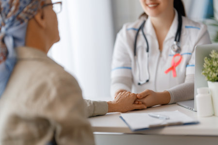 Pink ribbon for breast cancer awareness. Female patient listening to doctor in medical office. Support people living with tumor illness.の写真素材