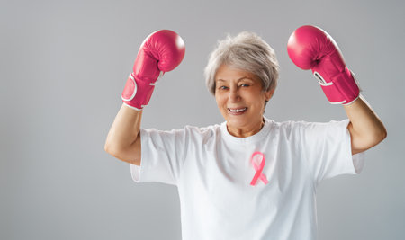 Woman in boxing gloves with a pink ribbon as a symbol of the fight against cancer. Increasing the level of knowledge about people who have overcome tumor diseases.の写真素材