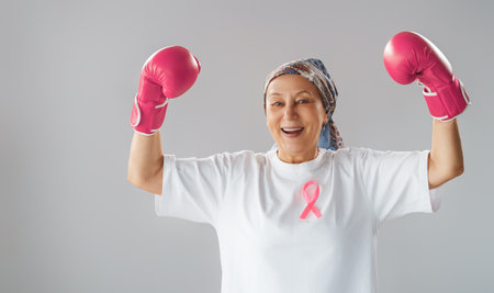 Woman in boxing gloves with a pink ribbon as a symbol of the fight against cancer. Increasing the level of knowledge about people who have overcome tumor diseases.の写真素材