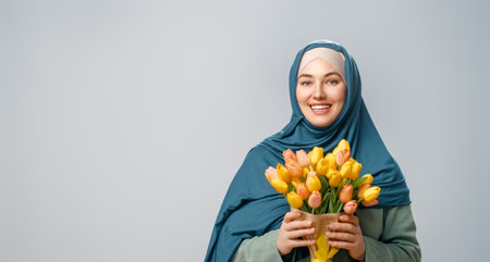 Beautiful young woman with yellow flowers in hands on grey wall background.の写真素材