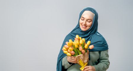 Beautiful young woman with yellow flowers in hands on grey wall background.の写真素材