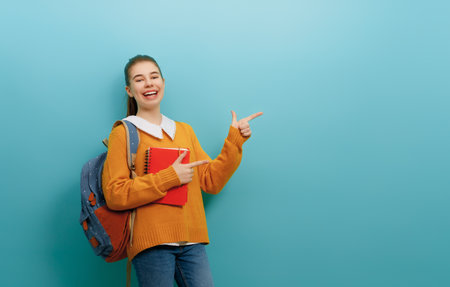 Back to school and happy time. Cute industrious teenager on color paper wall background. Girl with backpack. Teen ready to study.の写真素材