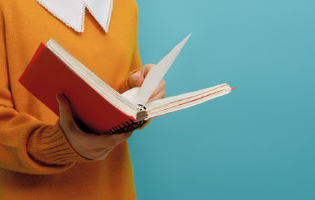 Back to school. Girl with book on background of bright teal wall.の写真素材