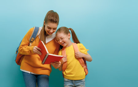 Two schoolers children standing on light blue background. Happy time back to school.の写真素材