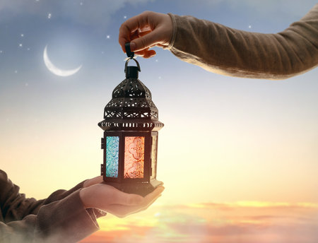 Ornamental Arabic lantern with burning candle glowing in hand. Festive greeting card, invitation for Muslim holy month Ramadan Kareem.の写真素材