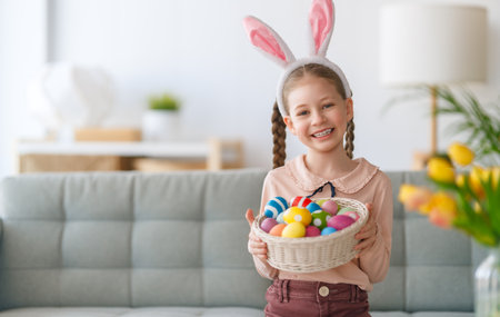 Beautiful child with painting eggs. Happy family preparing for Easter. Cute little girl is wearing bunny ears.の写真素材
