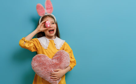 Cute little child wearing bunny ears on Easter day. Girl with painted egg.の写真素材