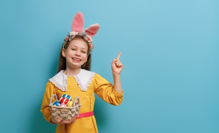 Cute little child wearing bunny ears on Easter day. Girl with painted eggs.