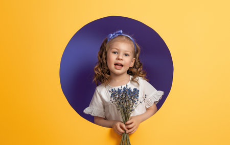 Cute child girl with a bouquet of lavender on yellow and purple background. Mothers day, spring concept.の写真素材