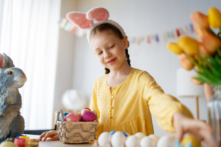 Beautiful child painting eggs. Happy family preparing for Easter. Cute little girl is wearing bunny ears.の写真素材