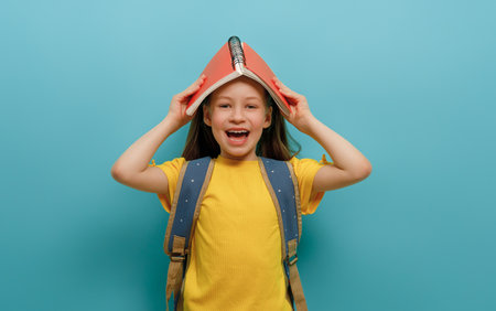Cute happy kid standing on light blue background. Child with backpack, little girl is ready to back to school.の写真素材