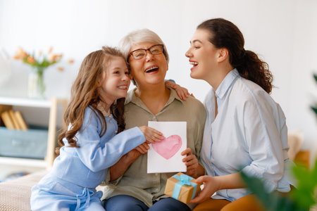 Happy mother's day. Child, mom and granny with gaft box and postcard. Grandma, mum and girl smiling. Family holiday and togetherness.の写真素材