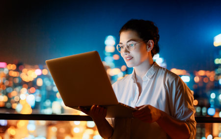 Young businesswoman standing near window with laptop.の写真素材