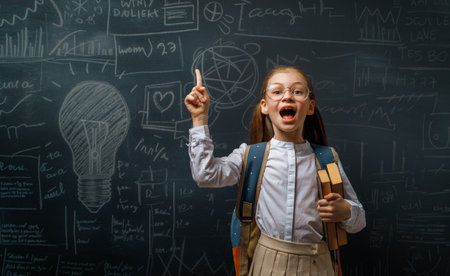 Back to school. Happy cute industrious child indoors. Kid is learning in class on background of blackboard.の写真素材