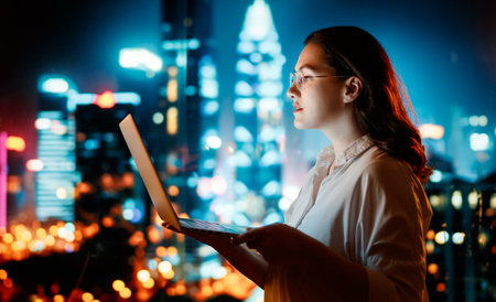 Young businesswoman standing near window with laptop.の写真素材