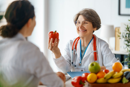 Happy doctor is working in medicine office. A woman is talking to a patient about the importance of eating fruits and vegetables.の写真素材