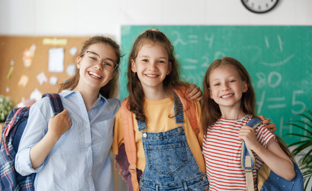Pupils of the school. Girls with backpacks in classroom. Teens are embracing. Beginning of lessons. First day of fall.の写真素材