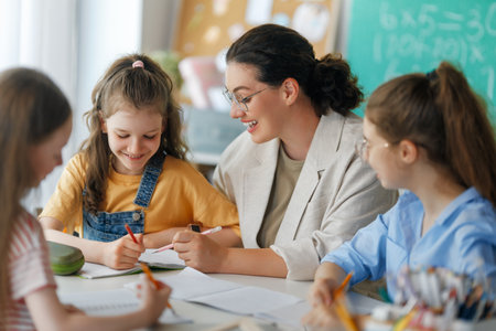 Happy kids and teacher at school. Woman and children are working in the class.の写真素材