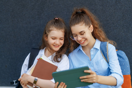 Pupils of the school. Girls with backpacks outdoors. Beginning of lessons. First day of fall.の写真素材