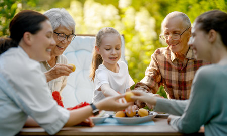 Happy family spending time together in summer morning. Family sitting in the garden and enjoying the conversation.の写真素材