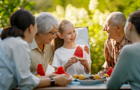 Happy family spending time together in summer morning. Family sitting in the garden and enjoying the conversation.の写真素材