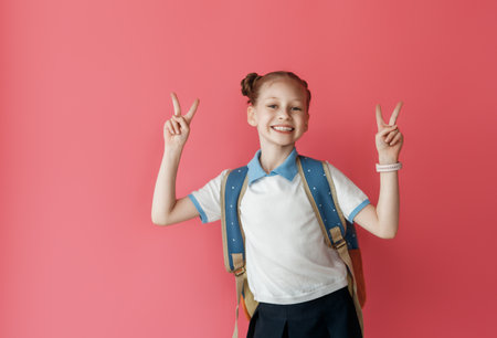 Cute happy teenager standing on bright pink background. Child with backpack, girl is ready to back to school.の写真素材