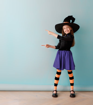 Beautiful laughing girl in Halloween witch costume on blue wall background.の写真素材