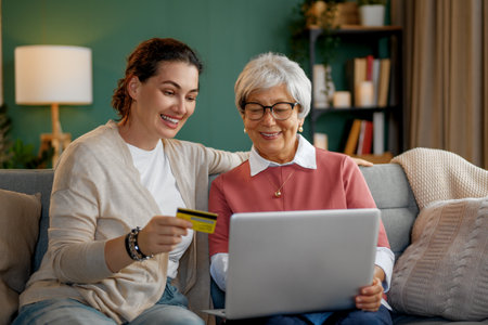 Young and senior women are using laptop pc for online shopping. Daughter is helping mother at home.の写真素材