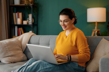 Happy casual beautiful woman using laptop at home.の写真素材