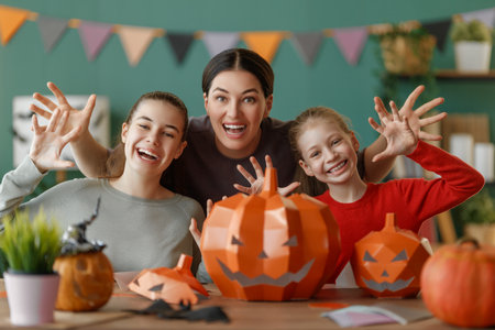 Happy family preparing for Halloween. Mother and children are cutting pumpkins at home.の写真素材