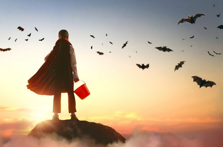 Little child in vampire costume at Halloween. Kid on sunset sky background.の写真素材