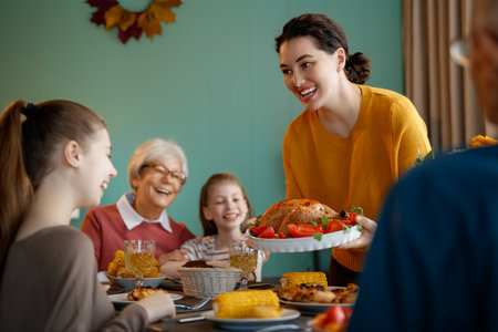 Happy Thanksgiving Day. Autumn feast. Family sitting at the table and celebrating holiday. Grandparents, mother and children. Traditional dinner.の写真素材