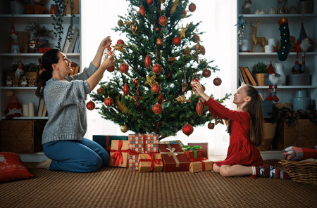 Merry Christmas, Happy Holidays. Mom and daughter near the tree indoors. The morning before Xmas.の写真素材