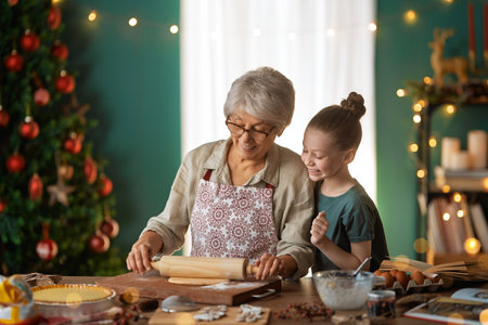 Merry Christmas and Happy Holidays. Family preparation holiday food. Grandmother and granddaughter cooking cookies.の写真素材