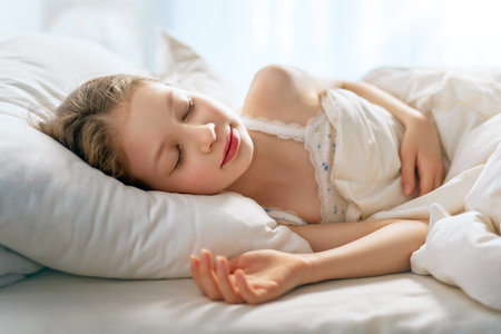 Adorable little girl is sleeping in the bed at home.の写真素材