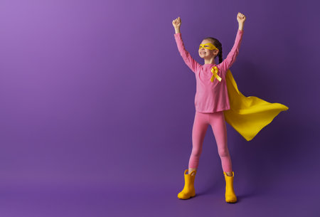 World Childhood cancer Day.  Girl in superhero costume with golden ribbon.の写真素材