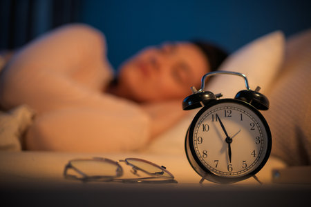 Woman is sleeping peacefully in her bedroom at night. Alarm clock in the foregroundの写真素材