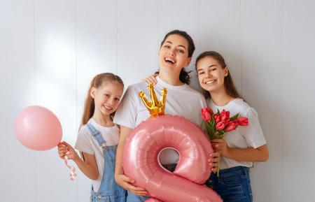Happy day. Children daughters are congratulating mother and giving her flowers. Family holiday and togetherness. Concept of International Women's Day.の写真素材