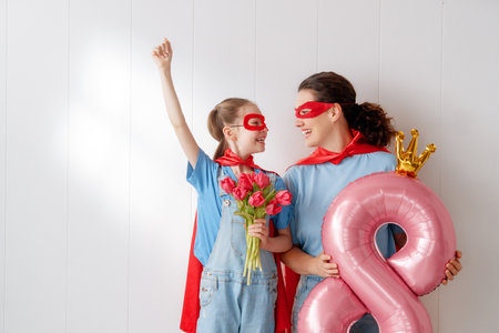 Happy day. Teenager daughter with mother celebrating International Women's Day and wearing superhero costumes. Family holiday and togetherness.の写真素材