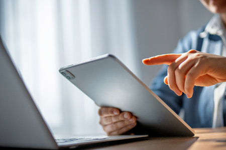 Woman is working in the office. Laptop, tablet pc and hands close up.の写真素材