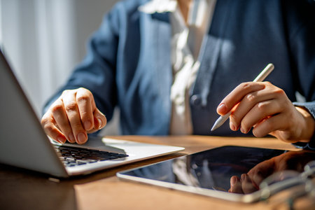 Woman is working in the office. Laptop, tablet pc and hands close up.の写真素材