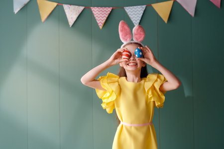 Cute little child wearing bunny ears on Easter day. Girl with painted eggs.の写真素材