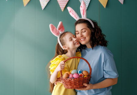 Cute little child wearing bunny ears on Easter day. Girl and mother with painted eggs.の写真素材