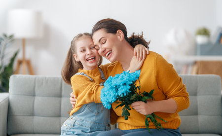 Happy mother's day. Child daughter is congratulating mom and giving her flowers. Mum and girl smiling and hugging. Family holiday and togetherness.の写真素材