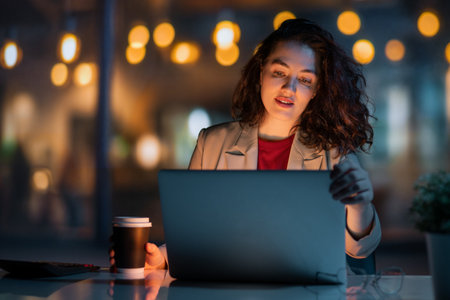 Young businesswoman working on laptop near window in the evening.の写真素材