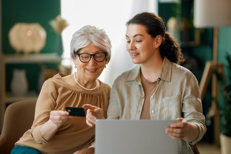 Young and senior women are using pc for online shopping. Daughter is helping mother at home.の写真素材