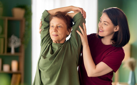 Senior woman doing exercise. A nurse helping with physical therapy at homeの写真素材