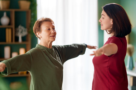 Senior woman doing exercise. A nurse helping with physical therapy at homeの写真素材