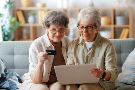 Women are doing online purchases. Senior people are doing shopping using laptop and credit card at home.の写真素材